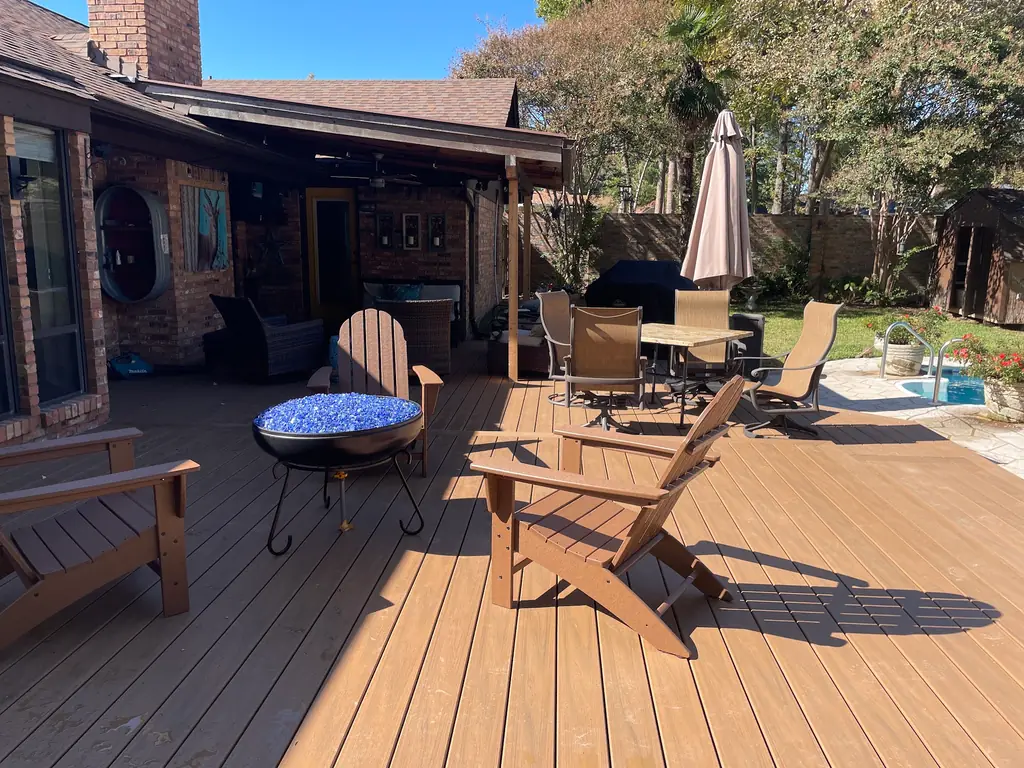 Wide composite deck with adirondack chairs and a fire bowl beside a pool
