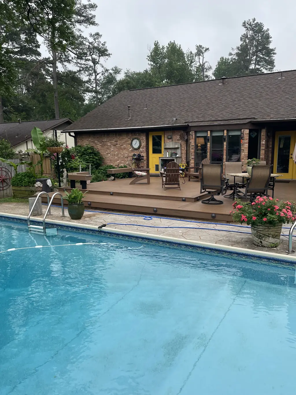 Composite pool deck stepping down to an in-ground pool at a brick ranch house