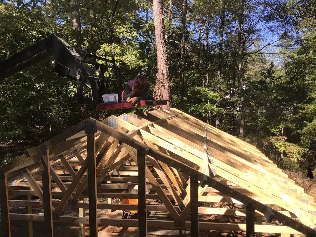 A Longview Decks crew member setting roof trusses on a timber pavilion